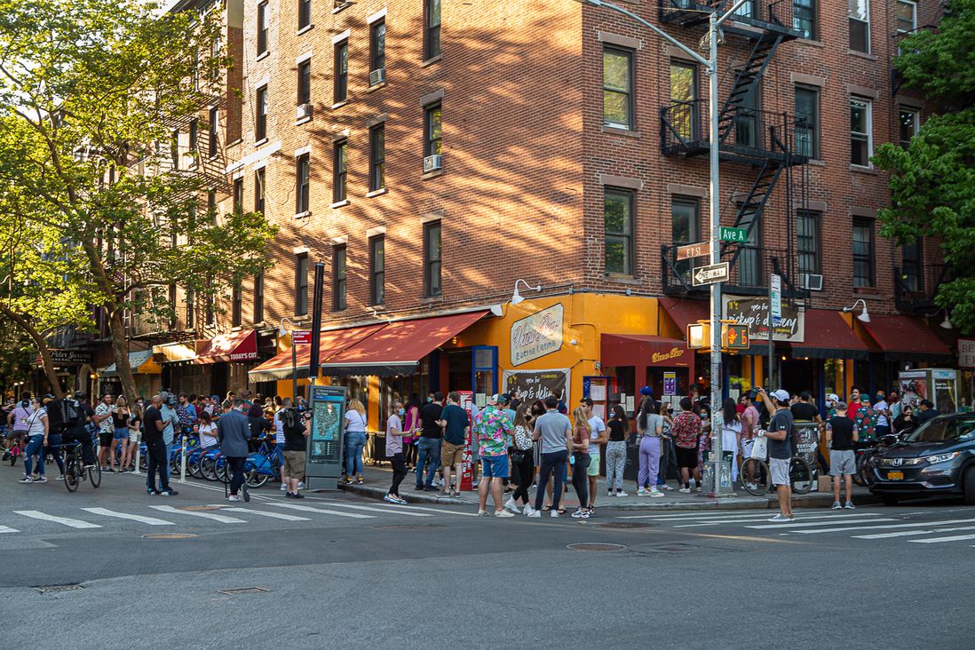 Groups of people in the streets and on the sidewalks outside of bars in the East Village
